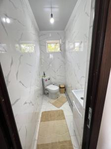 a bathroom with white marble walls and a toilet and a tub at Tunduk Guest House in Kochkor