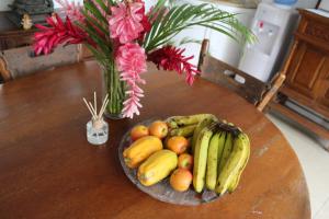 a bowl of fruit on a table with a vase of flowers at Residence71Nadi Fiji in Nadi