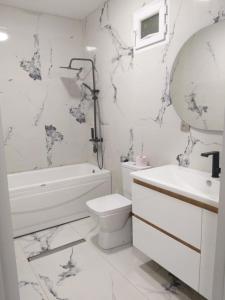 a white bathroom with a toilet and a tub and a sink at Goga Guest House in Kvariati