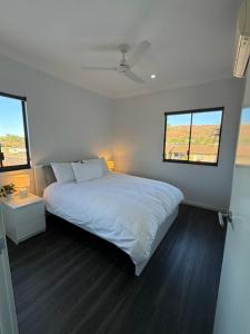 a white bedroom with a bed and two windows at Modern 2 Bedroom Apartment Karratha in Karratha +5 photos