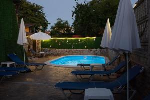 a pool with chairs and umbrellas in a yard at Marianas Guesthouse in Obzor