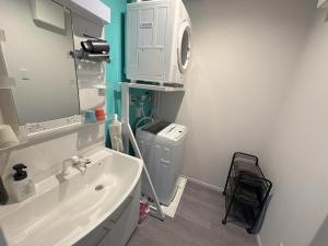 a bathroom with a sink and a washing machine at Crest Blue 402-オーシャンフロント! 新築マンション! in Kin