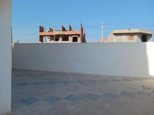 a white wall with a building in the background at soussoleil in Bin Rhilouf