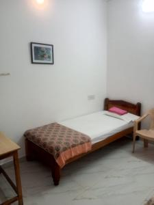 Un pequeño dormitorio con una cama y una silla. en G Shankara guest house, en Tiruvannāmalai