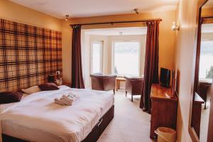 オニックにあるThe Lodge On The Loch Onichのベッドとテレビがあるホテルの部屋