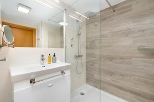 ein Bad mit einer Dusche mit einem Waschbecken und einer Duschkabine aus Glas in der Unterkunft Seaside Park by Solarento in Kołobrzeg + 26 Fotos