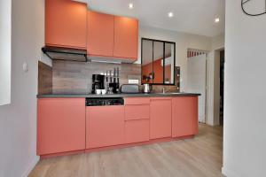 a kitchen with orange cabinets and black counter tops at Le Chic & Raffiné - Terrasse & Climatisé in Périgueux