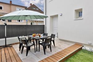a patio with a table with chairs and an umbrella at Le Chic & Raffiné - Terrasse & Climatisé in Périgueux