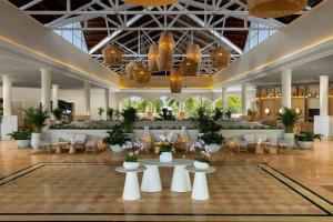 a lobby with tables and chairs in a building at Wyndham Alltra Punta Cana All Inclusive Resort in Punta Cana
