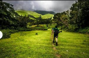 a man walking down a field with a backpack at Nelligudda Homestay in Kalasa +12 photos