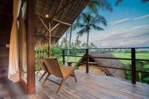 a porch with a chair and a view of the ocean at Supersenang Boutique Resort Balian in Balian