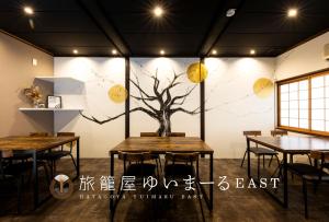 金泽ゆいまーるEAST - Yuimaru East的墙上有一棵树,桌子
