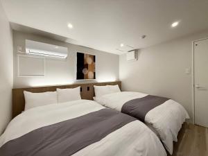 two beds in a small room with at Grandeur - Family-Sized Apt Near Peace Park with River View in Hiroshima