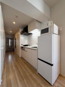 a kitchen with a white refrigerator and wooden floors at Grandeur - Family-Sized Apt Near Peace Park with River View in Hiroshima +26 photos