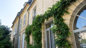 a building with ivy growing on the side of it at Les chambres de l'ATELIER à Montignac Lascaux in Montignac
