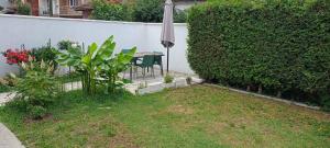 a garden with a table and an umbrella and a hedge at Gostinska kuća in Leskovac