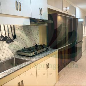 Una cocina con gabinetes blancos y un horno de estufa. en Warm Springs Villa 1, en Calambá