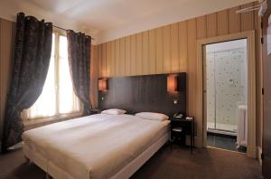 a bedroom with a large bed and a large window at Le Grand Hotel in Tours