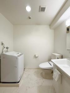 a white bathroom with a toilet and a sink at Grandeur - Bright Riverside Studio Walk to Peace Park in Hiroshima