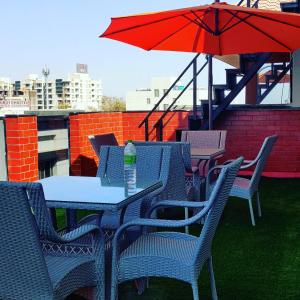 a table and chairs with an umbrella on a roof at Hotel Village Villa in Indore