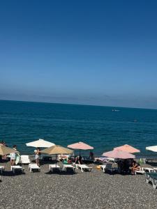 a group of people sitting on a beach with umbrellas at Mzeonas Apartment in K'obulet'i
