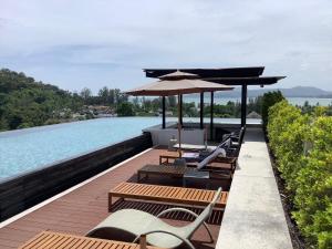 a deck with chairs and an umbrella and a pool at Superb Apartment! 5 Mins to the Beach in Ban Lum Fuang