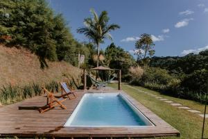 ein Pool mit einer Hängematte neben einem Holzdeck in der Unterkunft Luxo e Aconchego na Natureza - DM in Domingos Martins
