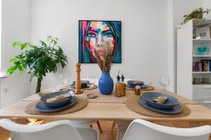 a dining room table with a painting of a woman at Stay COZY - TOP LAGE - Kingsize Betten - Parkplatz - Balkon - Netflix in Aschaffenburg