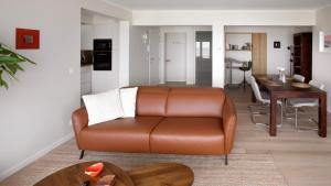 a living room with a brown leather couch and a table at Valdemosa one in De Haan