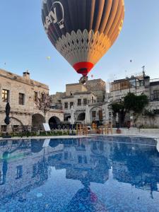 a hot air balloon flying over a swimming pool at Göreme Cave Suites in Göreme