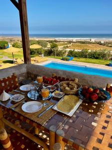 - une table de petit-déjeuner avec de la nourriture et une vue sur l'océan dans l'établissement Riad La Tempérance, à Essaouira