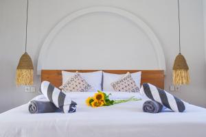 a white bed with flowers and pillows on it at Pandan Villas, Canggu in Dalung