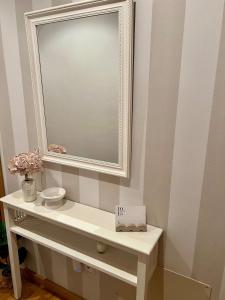 a bathroom with a mirror and a table with a sink at Apartamento tranquilo in Negreira +13 photos