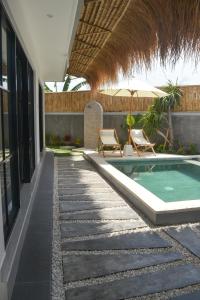 a patio with a swimming pool and chairs next to a building at Pandan Villas, Canggu in Dalung