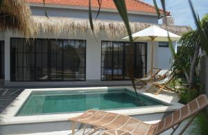 a swimming pool with two chairs and an umbrella at Pandan Villas, Canggu in Dalung