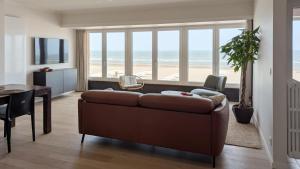 a living room with a couch and a table with a view of the beach at Valdemosa one in De Haan