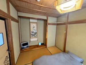 a small room with a bed and a television at Azetoshi Lodge in Nozawa Onsen