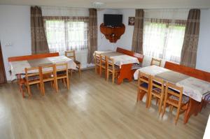 a dining room with tables and chairs and a television at Cabana Ioana in Munună