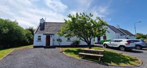 a white house with a car parked in front of it at Bluebell Cottage 3 bedroom in Louisburgh