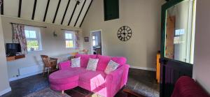 a living room with a pink couch and a table at Bluebell Cottage 3 bedroom in Louisburgh