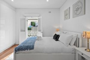 a white bedroom with a bed and a window at Harbour Glimpses & Modern Comfort in Sydney