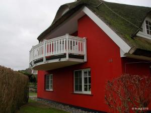 ein rotes Haus mit einem weißen Balkon darauf in der Unterkunft Landhaus Uhlenhof 4 in Groß Zicker