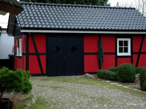 eine rote und schwarze Scheune mit weißem Fenster in der Unterkunft Landhaus Uhlenhof 4 in Groß Zicker