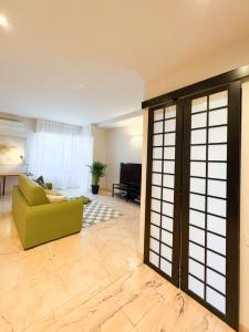 un soggiorno con divano verde e porta aperta di Borgo Design Apartment by the sea a Civitavecchia