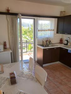 una cucina con tavolo e vista sul balcone di Villa Poseidon Artemisiou Παραθαλάσσια Βίλα στην βόρεια Εύβοια για φιλοξενία 9 ατόμων a Artemísion