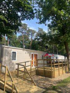 une remorque avec une terrasse et une clôture dans l'établissement Care-accessible Cosy Cottage 4 personen, à Kasterlee
