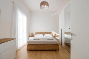 Un dormitorio blanco con una cama y un espejo. en Villa Francesca - Beach and Airport, en Carini