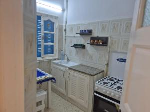 a kitchen with white cabinets and a sink and a stove at Résidence BAYA in Chott Meriem +5 photos