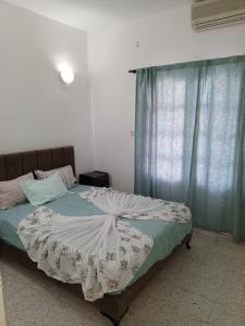 a bedroom with a large bed with blue curtains at Résidence BAYA in Chott Meriem