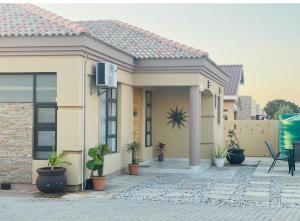 a house with potted plants in front of it at Palm Villa GuestHouse in Jwaneng
